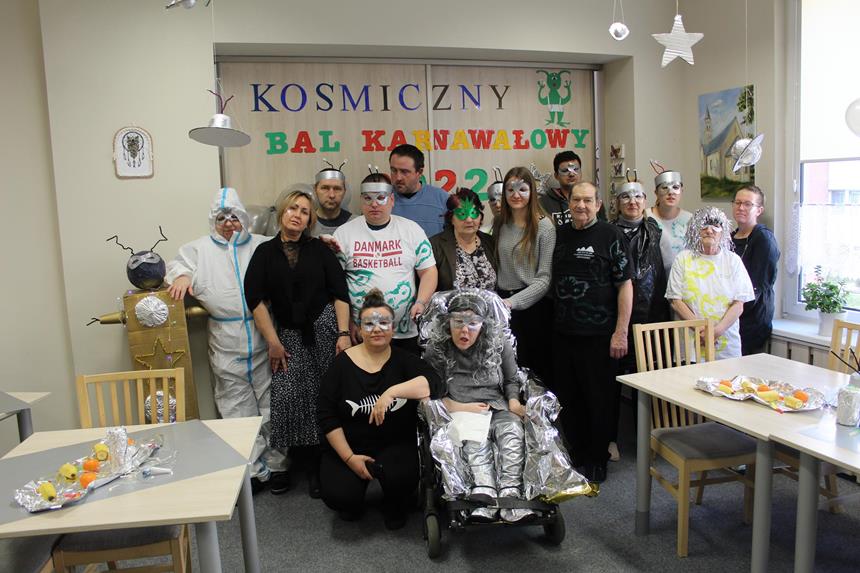 2 – Grupa Uczestników wraz z terapeutami pozują do zdjęcia na tle napisu