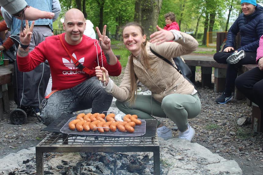 1.Fizjoterapeutka oraz uczestnik pozują do zdjęcia przed kiełbaskami na grillu D