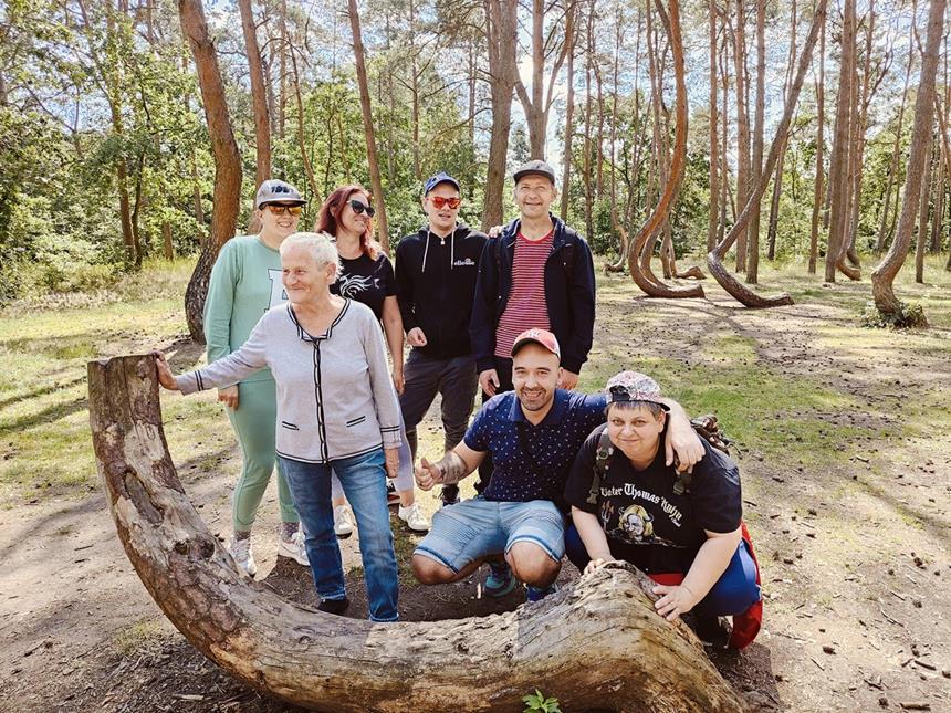 1.Uczestnicy pozujący do zdjęcia za ściętym krzywym drzewem D