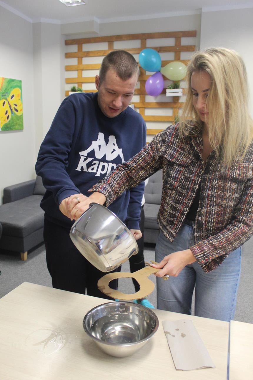 1.Pani Pedagog oraz uczestnik przelewający wosk przez klucz do miski z wodą D