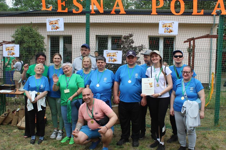 Uczestnicy oraz organizatorzy pozujący do zdjęcia na tle napisu „Leśna Polana” 