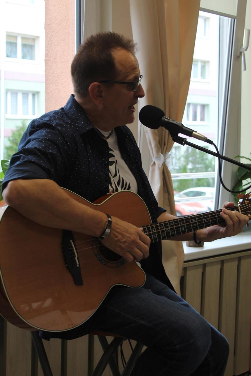 1.Pan Janusz w ciemnej koszuli śpiewający oraz grający na gitarze D