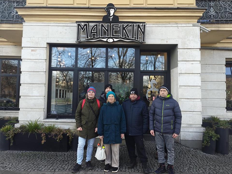 Uczestnicy stojący przed wejściem na tle napisu Manekin