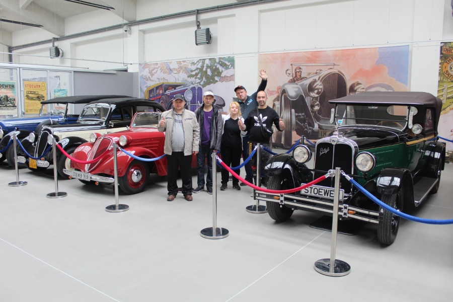 Uczestnicy pozujący do zdjęcia przy zabytkowych samochodach.