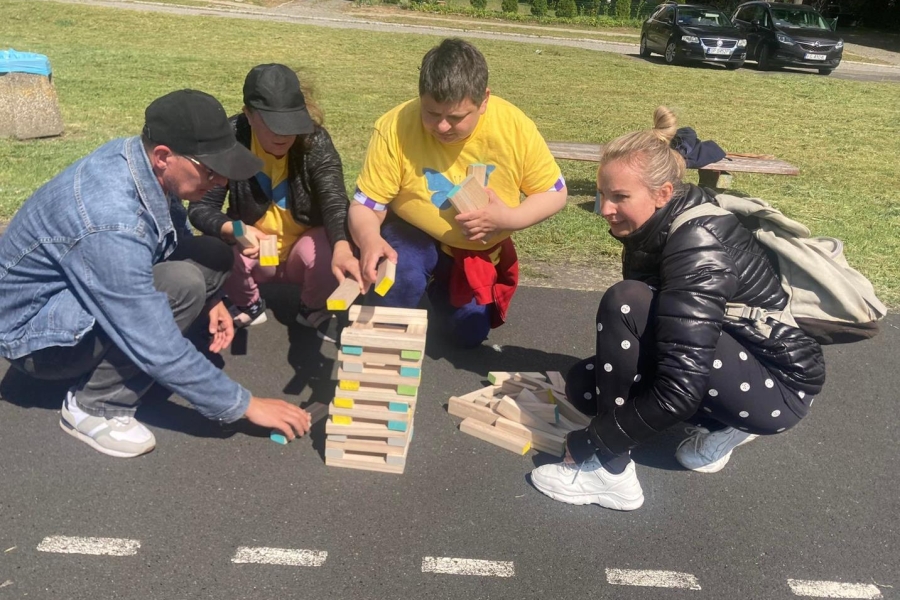 Uczestnicy wraz z terapeutą budują wieżę z drewnianych kloców.