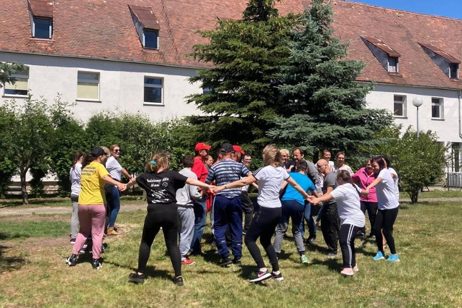 Grupa Uczestników podczas wspólnej zabawy trzyma się za ręce.
