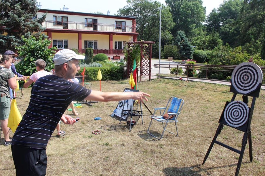 Uczestnik celuje lotką do tarczy.
