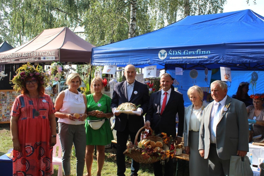 1. Pani Kierownik ŚDS w Gryfinie wraz z Burmistrzem Gryfina pozują do zdjęcia grupowego na tle namiotów. 