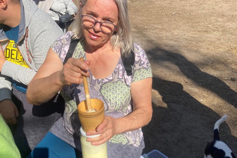 3. Uczestniczka siedząca na ławce wyrabia masło.