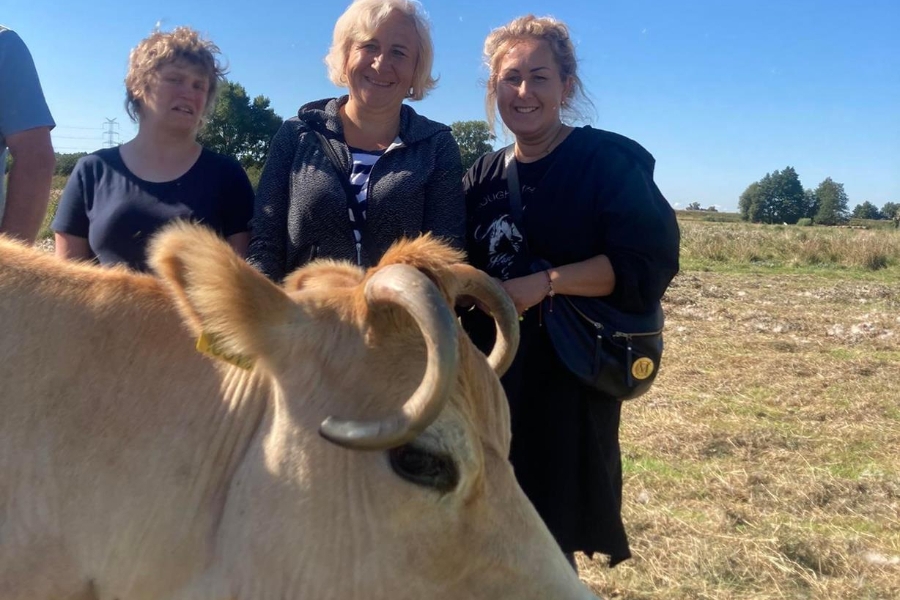 5. Uczestniczka wraz z mamą i terapeutką pozuje do zdjęcia z krową.