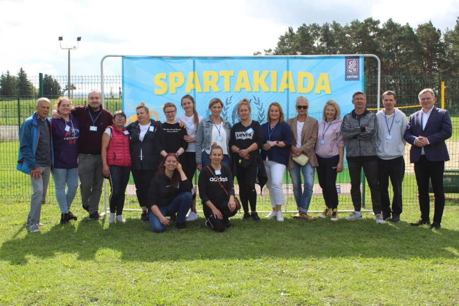 12. Organizatorzy Spartakiady pozują do zdjęcia grupowego na tle baneru. 