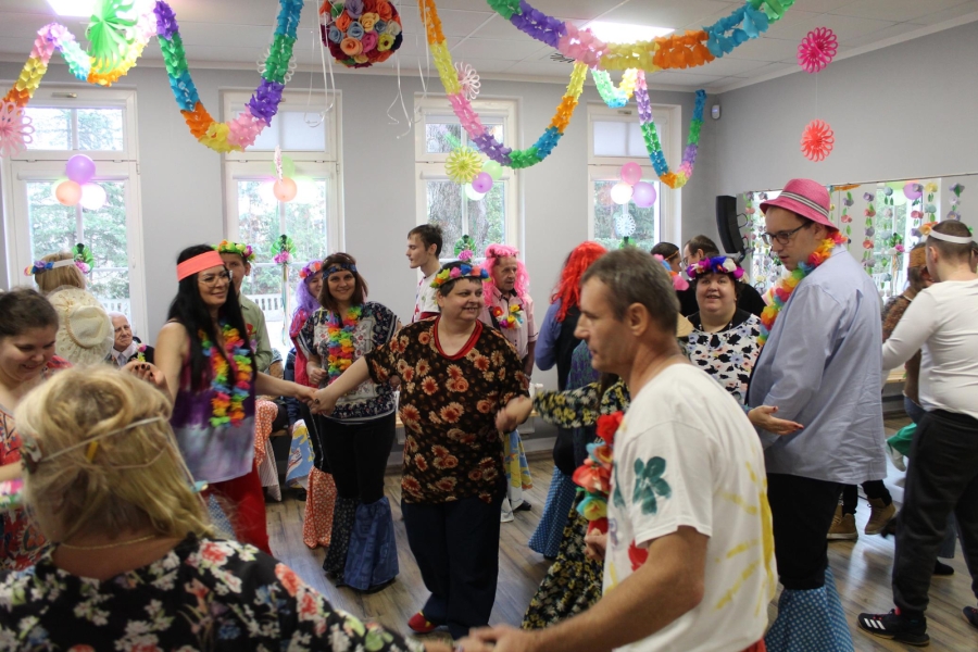 3. Grupa uczestników w kolorowych strojach tańcząca w kółku