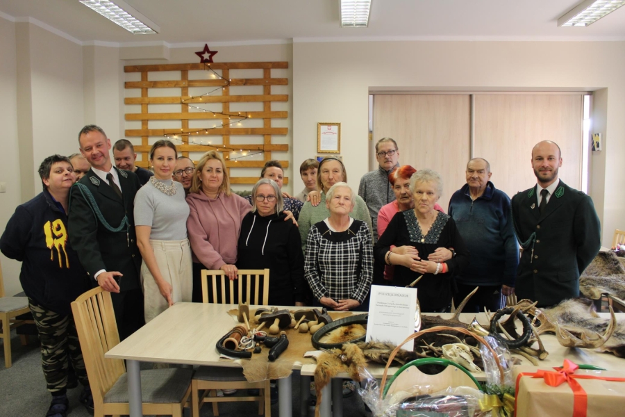 1.Trofea oraz akcesoria myśliwskie na tle grupy osób 