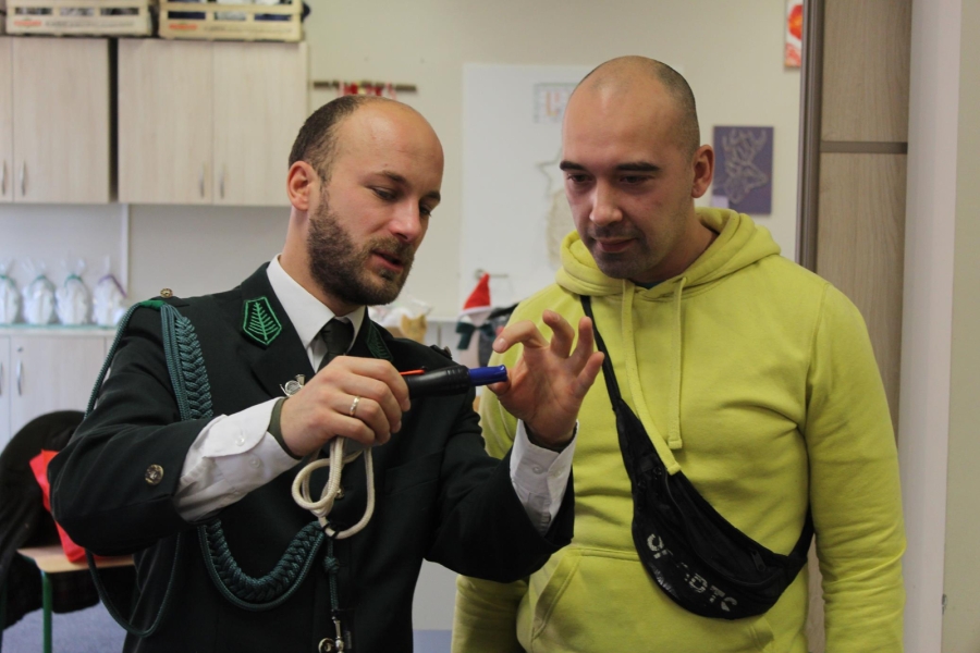 3.Pan w mundurze myśliwskim pokazujący gwizdek myśliwski uczestnikowi