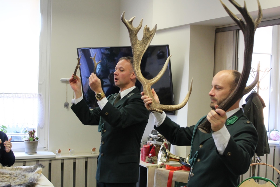 4.Dwoje myśliwych prezentujących poroża jelenia oraz koziołka