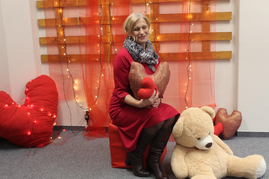 4.Kierownik ŚDS w Gryfinie trzymająca serce z materiału na tle pluszowego misia oraz czerwonych lampek