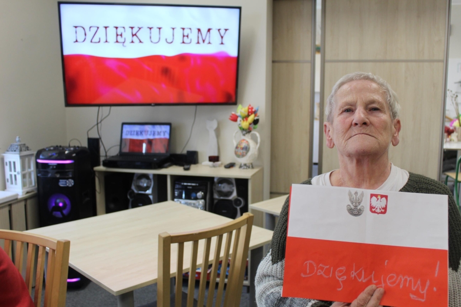 3.Uczestniczka trzymająca biało czerwoną pracę na tle napisu „Dziękujemy”