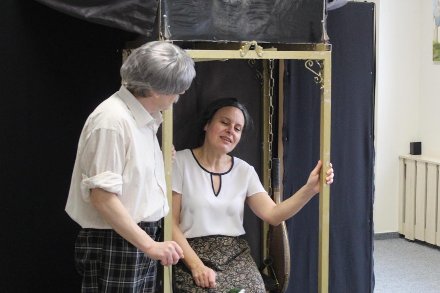 2.Aktor mówiący co siedzącej aktorki z kwiatem w dłoni pod zegarem