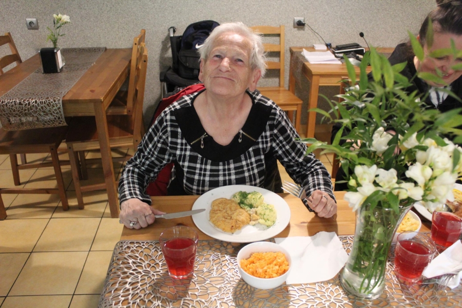 2.Uczestniczka uśmiechająca się na tle obiadu