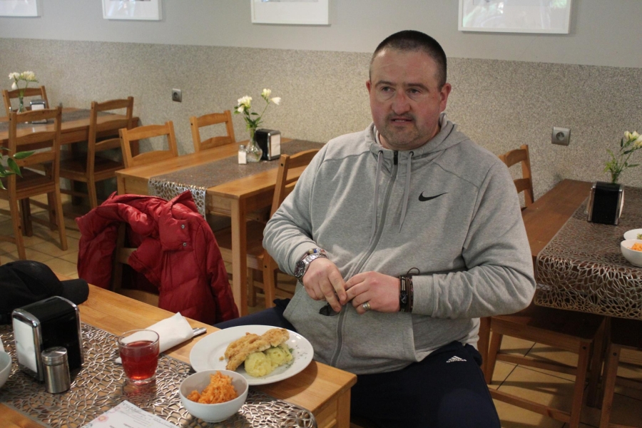 4.Uczestnik uśmiechający się do zdjęcia na tle obiadu w restauracji