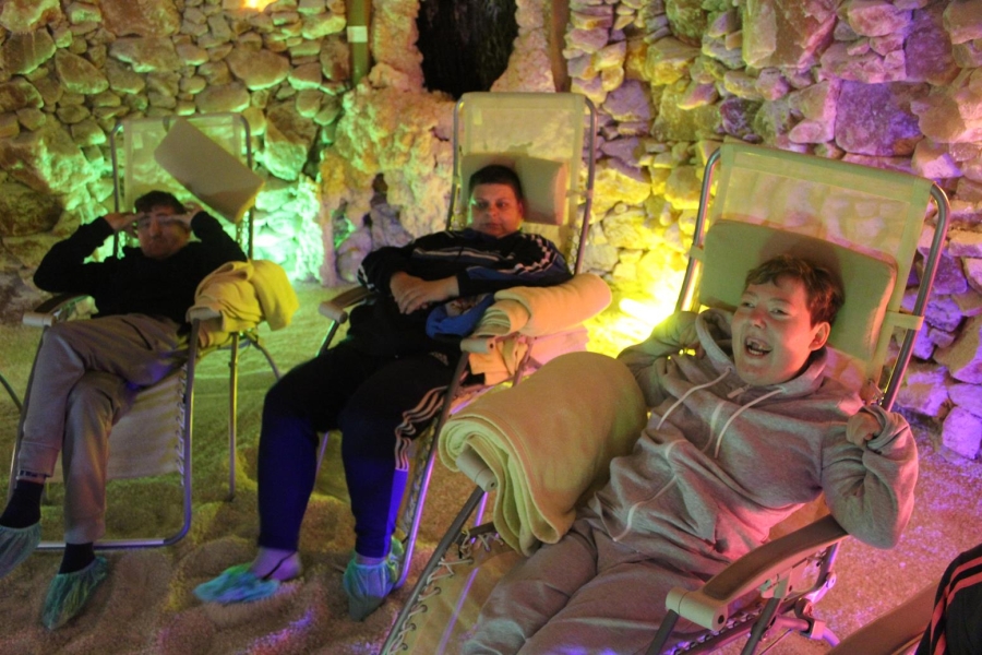 2.Uczestnicy śpiący na leżakach w komnacie solnej na tle kolorowych świateł