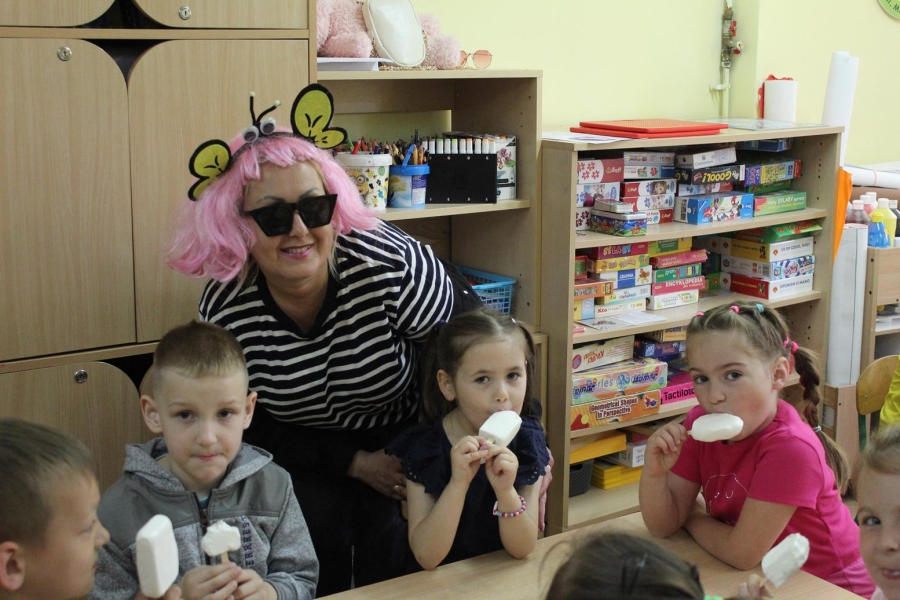 4.Terapeuta w stroju pszczółki uśmiecha się do zdjęcia z dziećmi jedzącymi lody przy stole