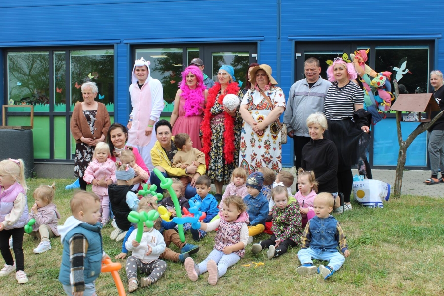 6.Uczestnicy w żłobku oraz dzieci w kolorowych strojach pozują do zdjęcia na świeżym powietrzu