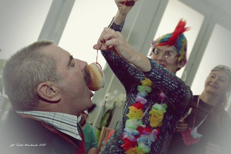 Uczestniczka wkładająca pączka na sznurku do buzi uczestnikami