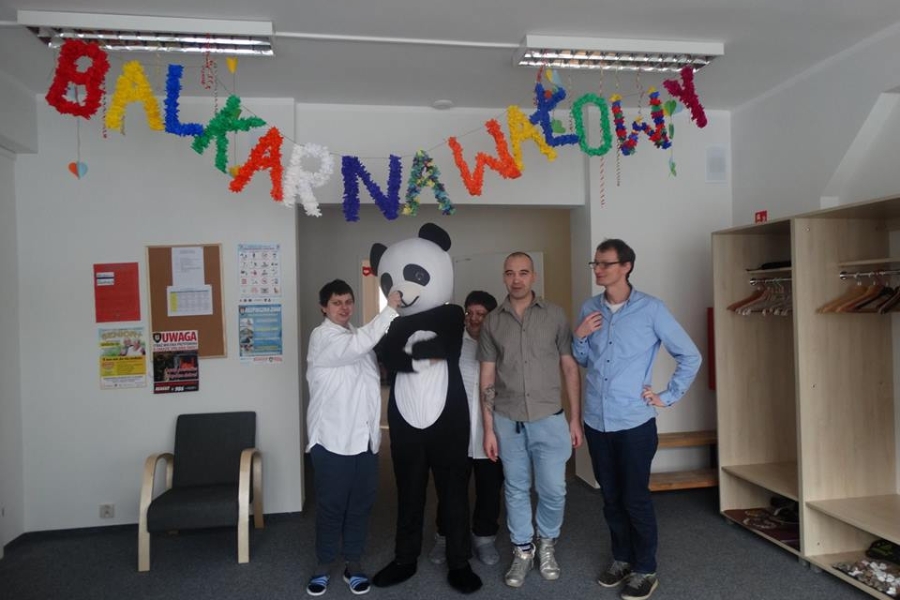 Uczestnicy oraz gość w przebraniu pandy na tle napisu bal karnawałowych