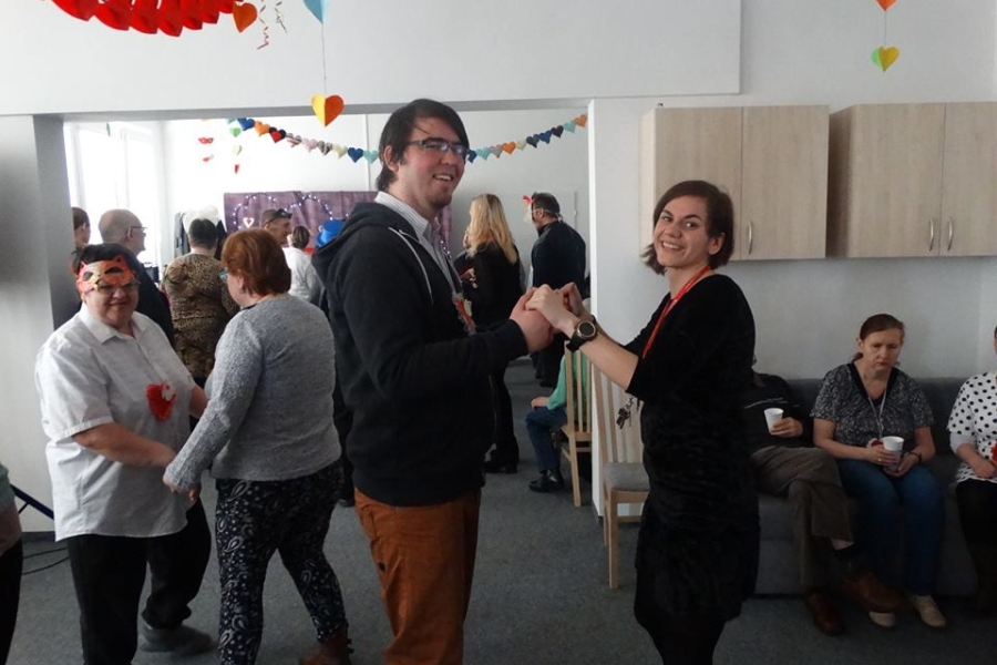 Uczestnik wraz z terapeutką trzymający się za ręce na tle zabawy