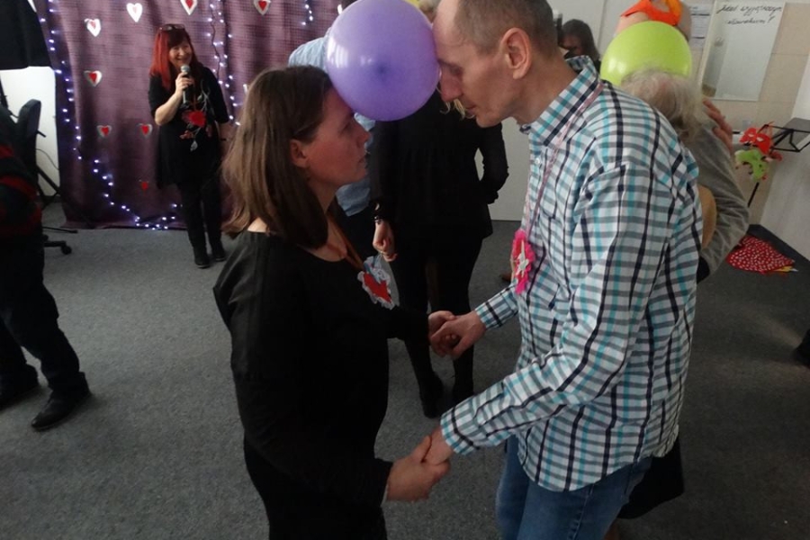 Uczestnicy tańczący z balonem między głowami