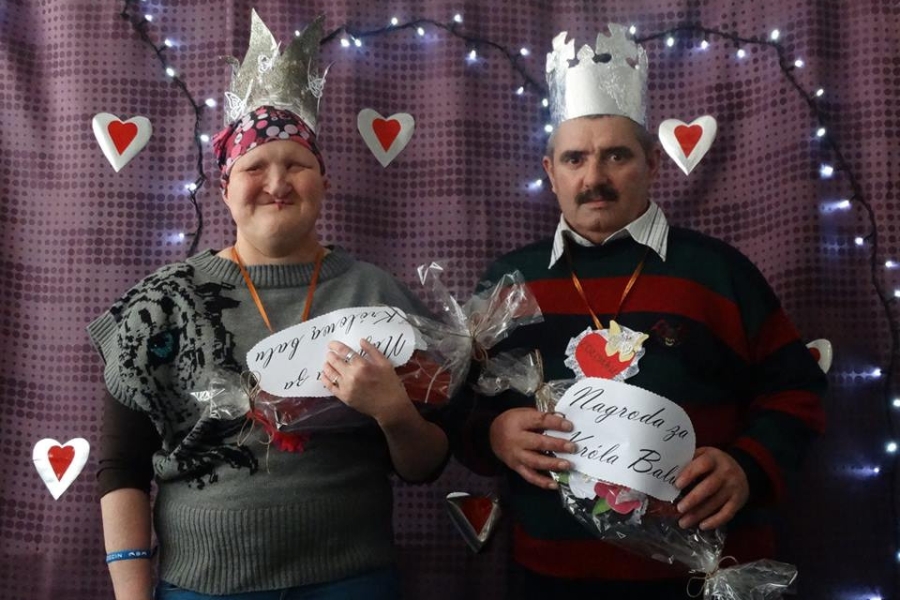 Dwoje uczestników z koronami na głowach trzymający upominki 