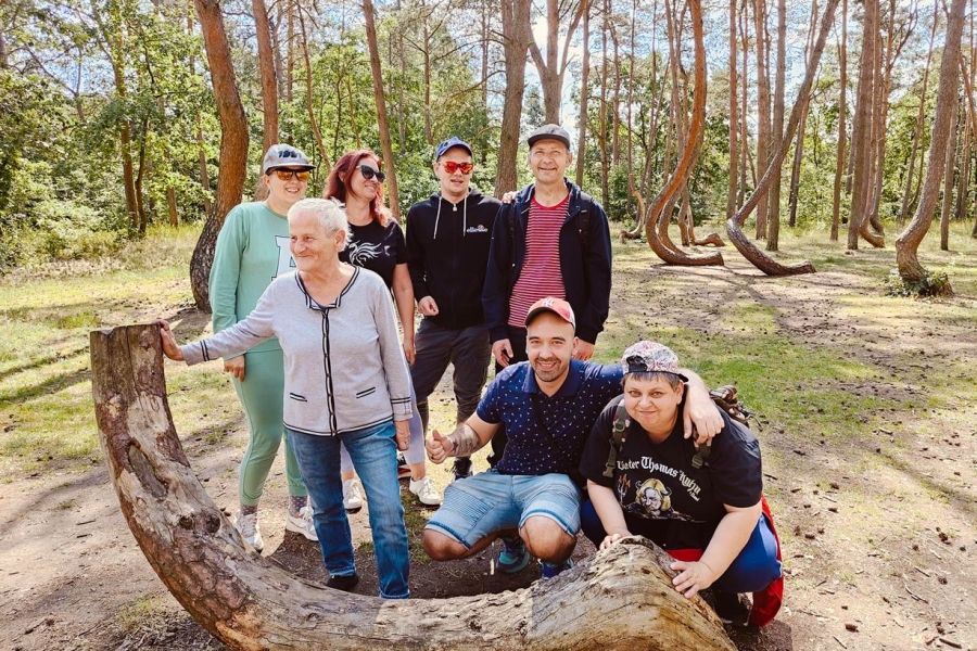 1.Uczestnicy pozujący do zdjęcia za ściętym krzywym drzewem