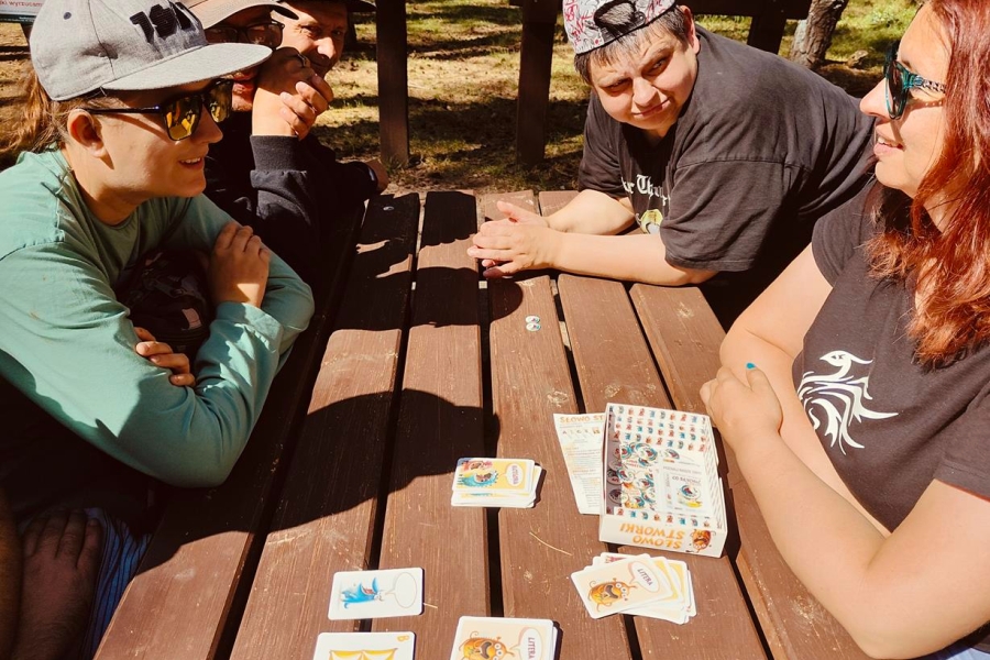 6.Uczestnicy oraz terapeutka grają w arty przy drewnianym stole