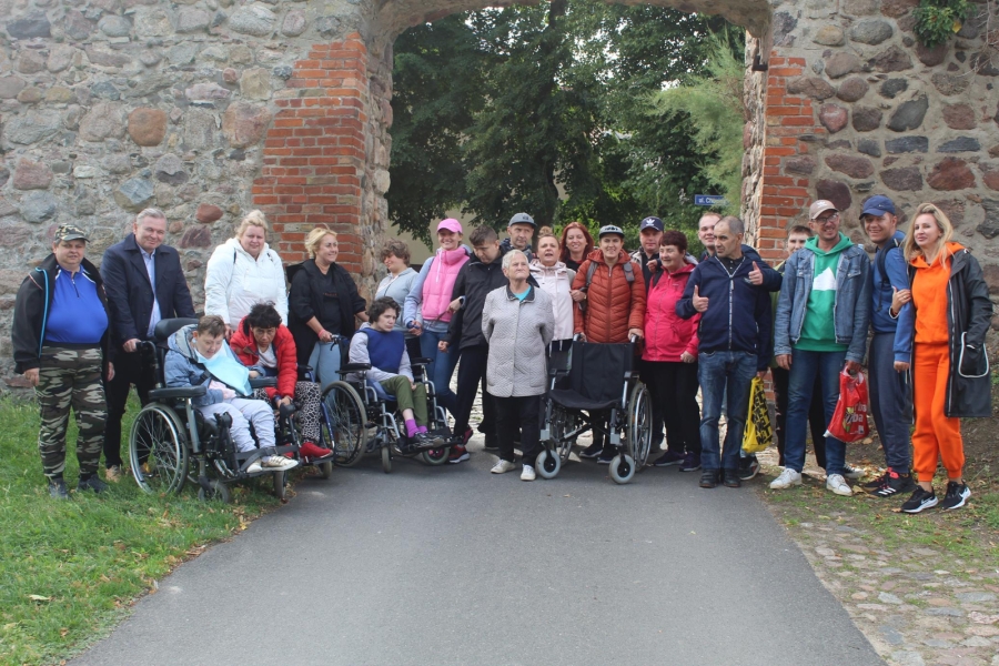 1.Grupa uczestników oraz pracowników stojąca przed kamienną bramą w moryniu