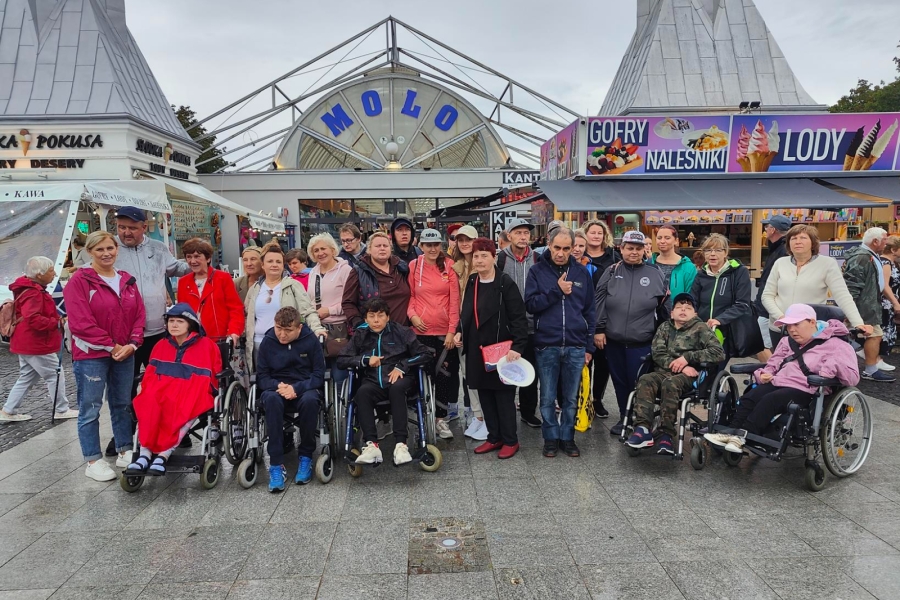 1.Uczestnicy, opiekunowie, terapeuci oraz Pani Kierownik stojący przed wejściem na molo w Międzyzdrojach
