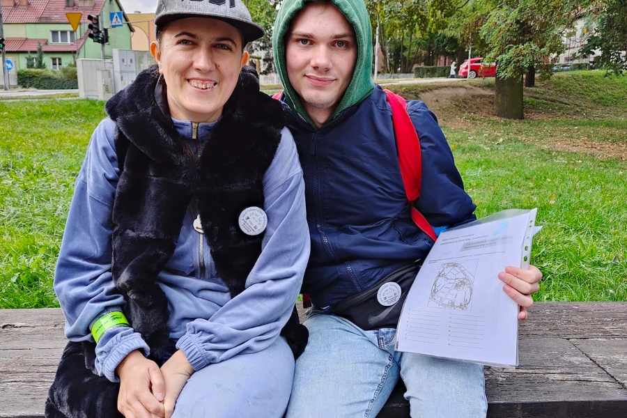 4.Uczestniczka oraz uczestnik siedzą na ławce na tle parku