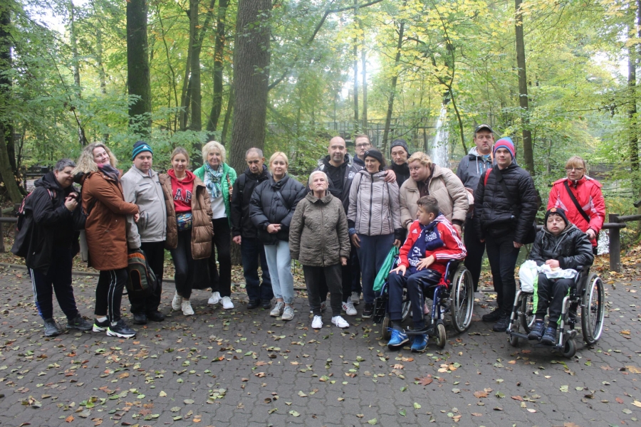 1.Grupa uczestników oraz terapeutów na tle drzew oraz fontoanny