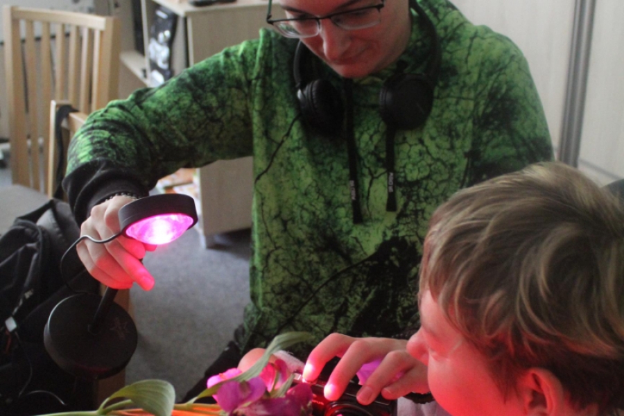 5.Uczestniczka wykonująca zdjęcie oraz instruktor kierujący światło lampy w stronę kwiatów