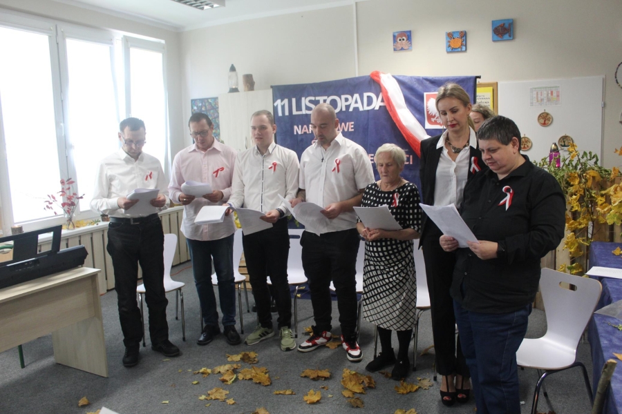 6.Uczestnicy oraz kadra stojący śpiewając pieśni patriotyczne na tle napisu 11 listopada