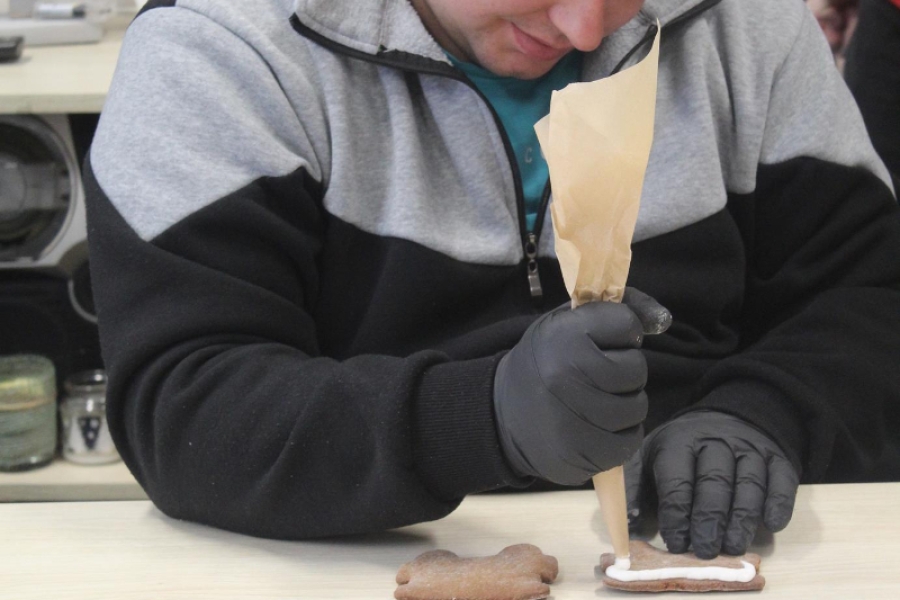 2.Uśmiechający się uczestnik ozdabiający piernikowe ciasto lukrem