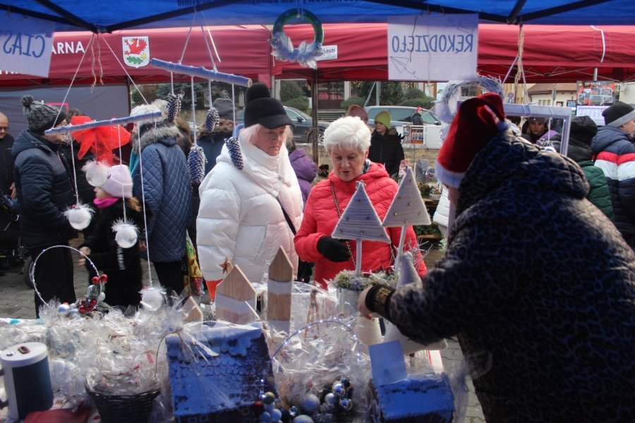 3.Pracownik w czapce Mikołaja prezentujący choinki dwóm Paniom na tle innych ludzi