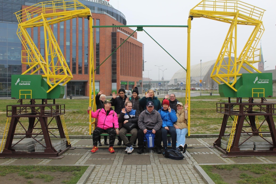 1.Uczestnicy oraz fizjoterapeutka siedzący na huśtawce o wyglądzie dźwigów