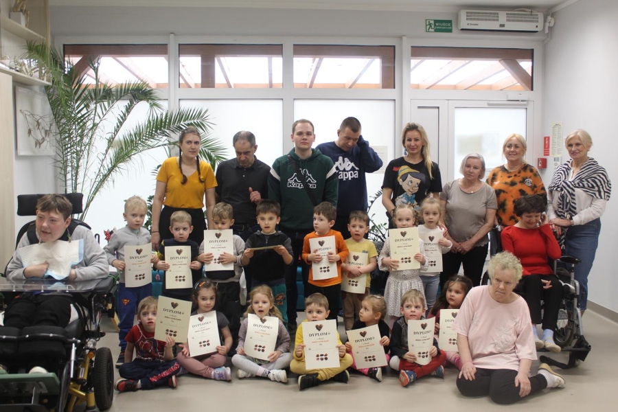 1.Kadra ŚDS w Gryfinie oraz Kadra i dzieci z przedszkola uśmiechający się do zdjęcia prezentujący dyplomy.