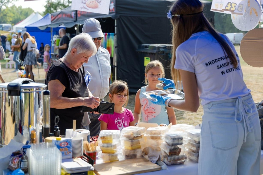 3.Fizjoterapeutka podająca ciasto Pani z dziećmi na tle ludzi