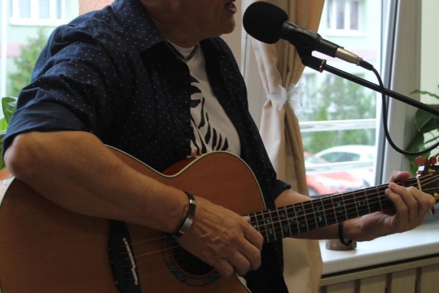 1.Pan Janusz w ciemnej koszuli śpiewający oraz grający na gitarze