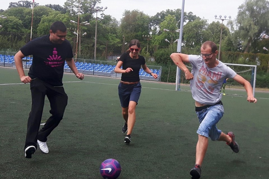 Uczestnicy wraz z terapeutką biegnących w stronę piłki