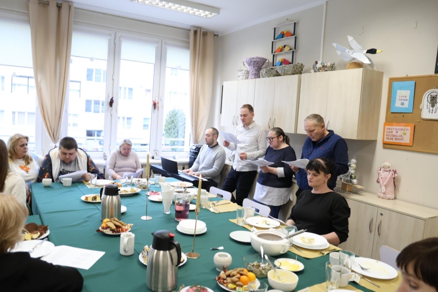 3.Uczestnicy na tle stołu wigilijnego śpiewający kolędy