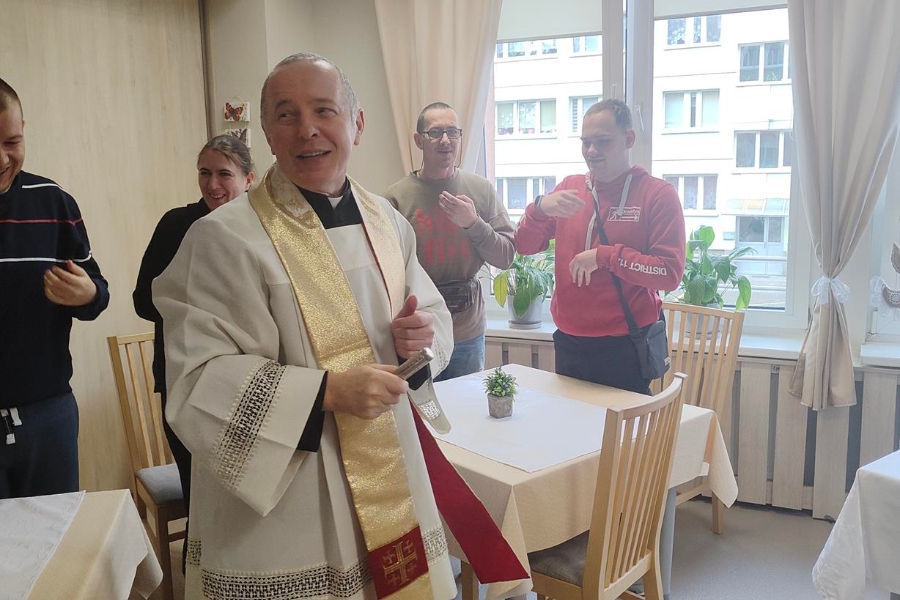 1.Ksiądz trzymający kropidło na tle modlących się osób