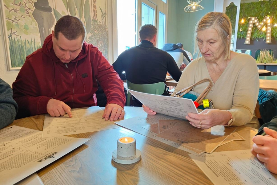 3.Uczestnik oraz uczestniczka czytający menu przy stole w restauracji